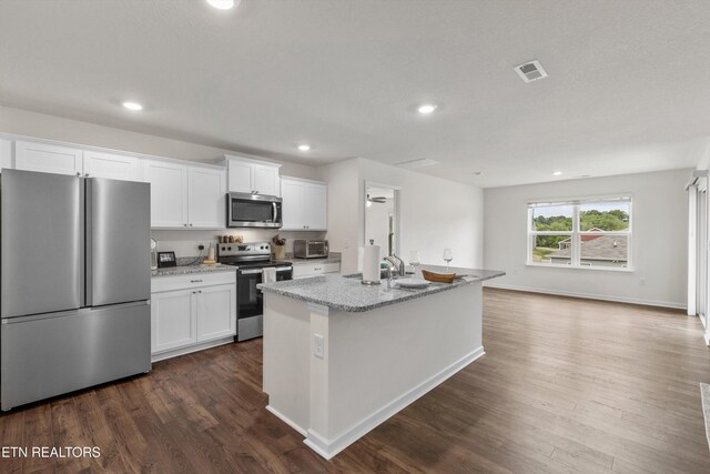 7813 Night Shade Ln, Knoxville, TN 37938 - kitchen featuring stainless steel appliances, white cabinetry, dark wood-style flooring, an island with sink, and light stone countertops