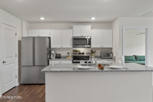 7813 Night Shade Ln, Knoxville, TN 37938 - kitchen with stainless steel appliances, white cabinets, dark wood-type flooring, a center island with sink, and light stone countertops