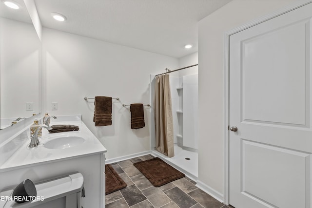 7813 Night Shade Ln, Knoxville, TN 37938 - full bathroom featuring a shower stall, stone finish flooring, baseboards, recessed lighting, and double vanity