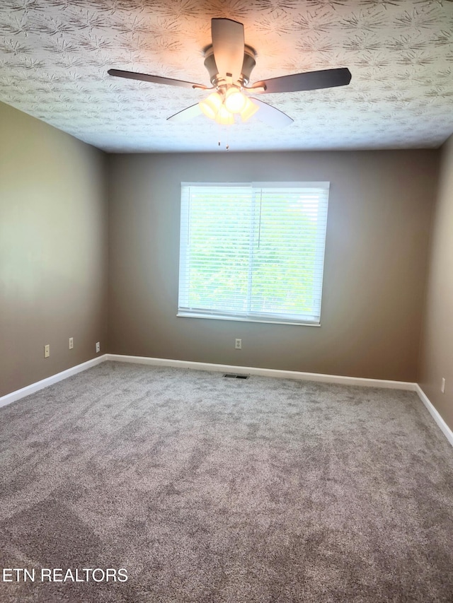 carpeted spare room with a ceiling fan, baseboards, and a textured ceiling