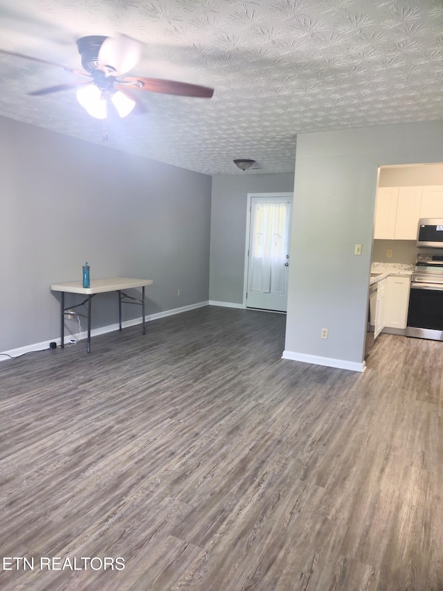 unfurnished living room with dark wood-style flooring, ceiling fan, and baseboards