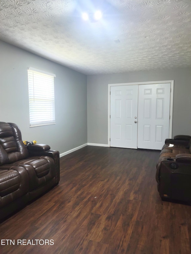 living area with dark wood-style flooring, baseboards, and a textured ceiling