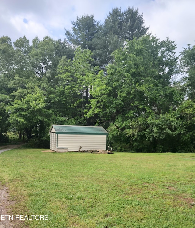 view of green lawn with a storage shed and an outbuilding