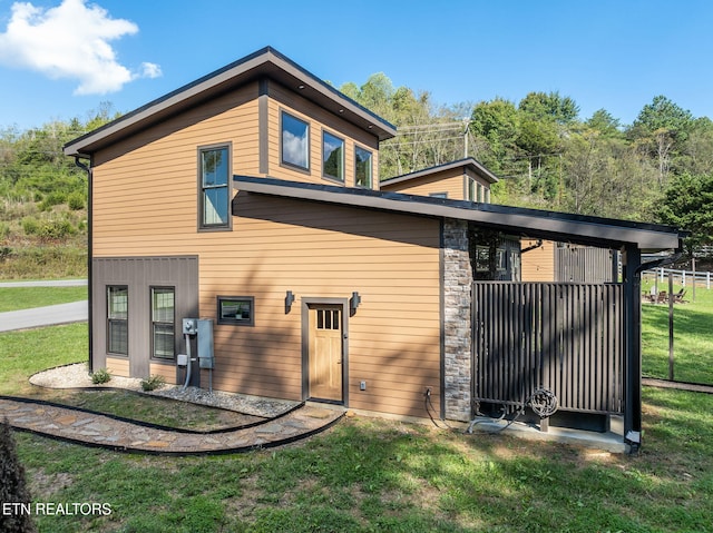back of house with a lawn and stone siding