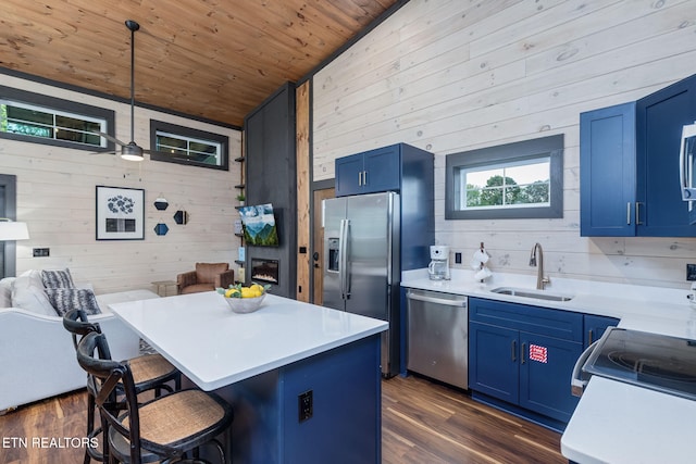 kitchen featuring a sink, stainless steel appliances, wooden walls, blue cabinets, and wooden ceiling