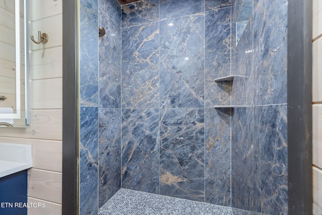 bathroom with a tile shower and vanity