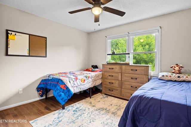 bedroom featuring wood finished floors, a ceiling fan, a textured ceiling, and baseboards