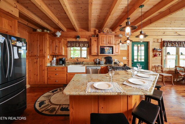2266 Lone Ridge Dr, Sevierville, TN 37862 - kitchen featuring appliances with stainless steel finishes, beam ceiling, wood-type flooring, wood walls, and a kitchen bar