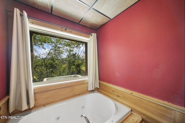 bathroom with a tub with jets and a textured wall