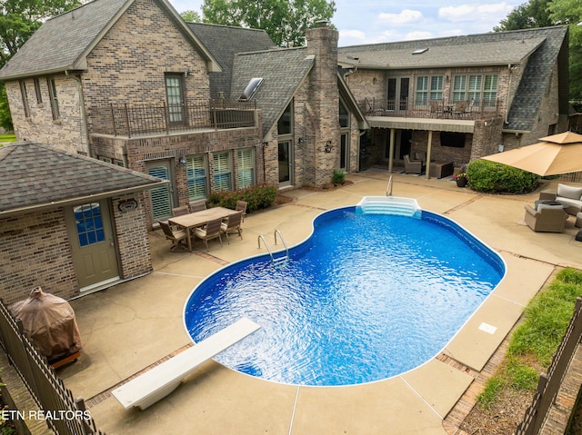 swimming pool with an outdoor living space, a patio area, outdoor dining area, and a diving board