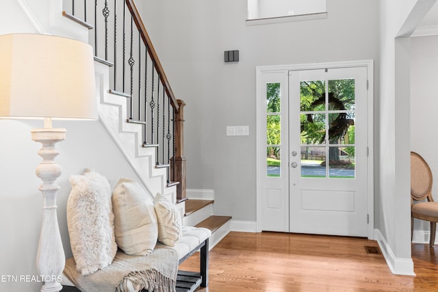 foyer featuring wood finished floors, stairs, baseboards, and a high ceiling