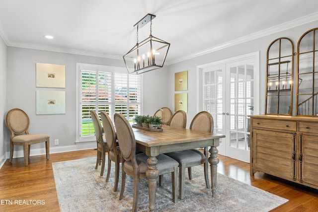 dining space featuring a chandelier, french doors, ornamental molding, baseboards, and wood finished floors