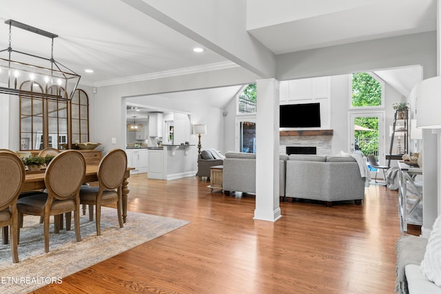 dining room featuring a fireplace, a chandelier, light wood-style flooring, recessed lighting, and ornamental molding