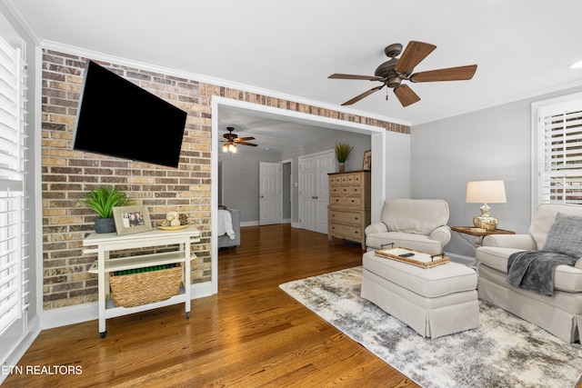 living area with a ceiling fan, wood finished floors, crown molding, and baseboards
