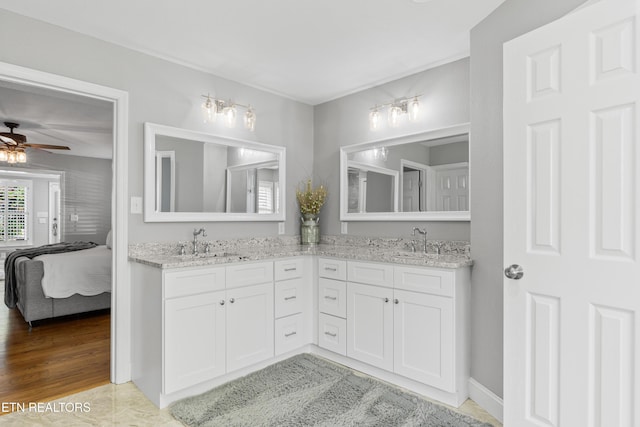 full bath with ensuite bath, double vanity, and ceiling fan