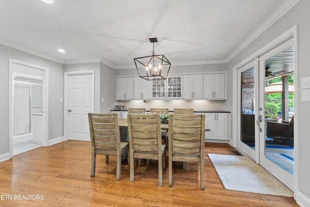 dining area featuring a chandelier, recessed lighting, light wood-type flooring, crown molding, and french doors