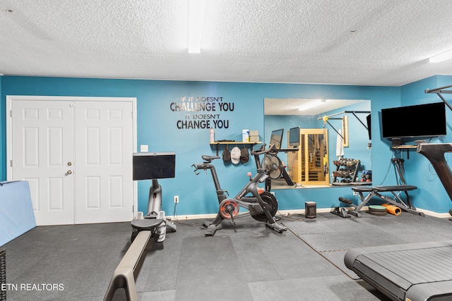 exercise area featuring a textured ceiling and baseboards