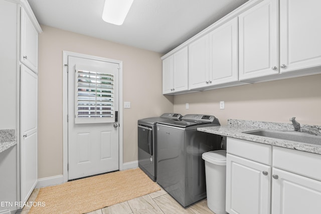 clothes washing area featuring independent washer and dryer, cabinet space, and baseboards