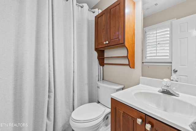 bathroom featuring toilet, vanity, and a shower with curtain
