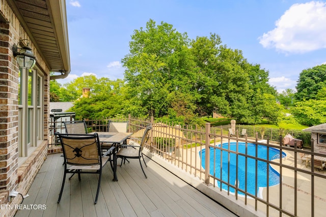 wooden terrace featuring outdoor dining area, fence, and view of scattered trees