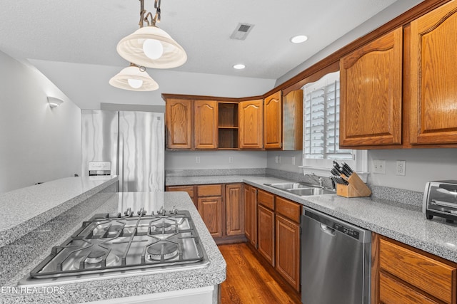 kitchen featuring stainless steel appliances, a sink, light countertops, brown cabinetry, and recessed lighting