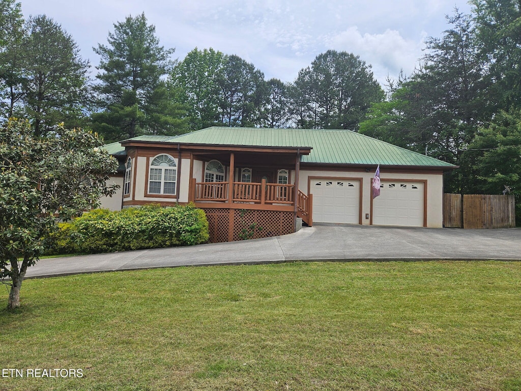 ranch-style house featuring driveway, an attached garage, metal roof, a porch, and stucco siding