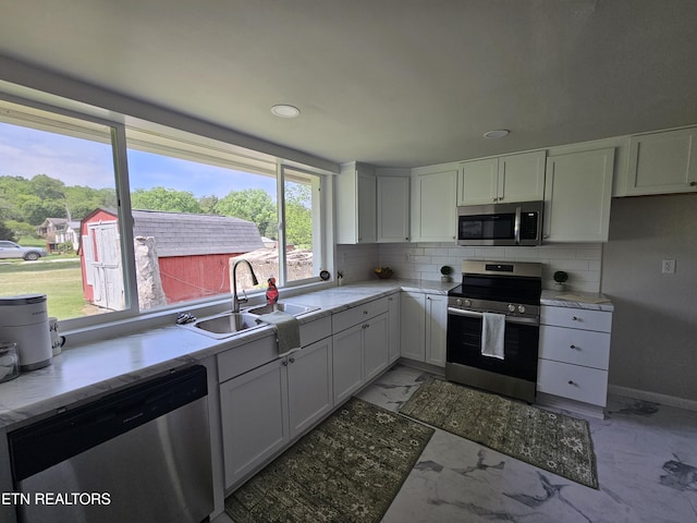 335 Bristol Rd, Harrogate, TN 37752 - kitchen with stainless steel appliances, a sink, light marble finish flooring, backsplash, and white cabinets