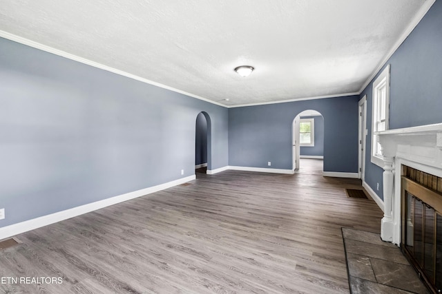 308 Nash Rd, Knoxville, TN 37914 - unfurnished living room featuring arched walkways, ornamental molding, a glass covered fireplace, wood finished floors, and baseboards