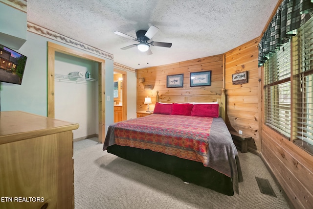 carpeted bedroom featuring wood walls, a textured ceiling, a closet, and ceiling fan