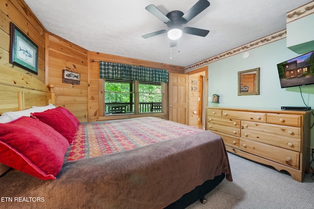 bedroom featuring carpet floors, wooden walls, a textured ceiling, and ceiling fan