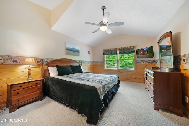 bedroom with vaulted ceiling, wainscoting, light colored carpet, and wood walls
