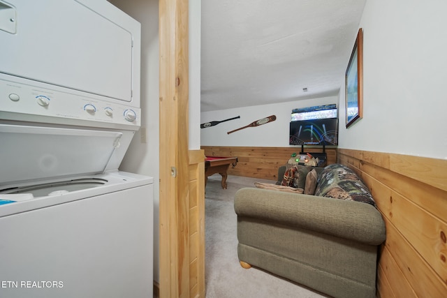 laundry area featuring stacked washer / drying machine, carpet, a wainscoted wall, pool table, and wooden walls