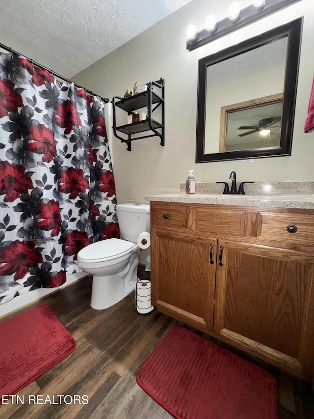 full bathroom featuring wood finished floors, toilet, vanity, a shower with shower curtain, and a textured ceiling