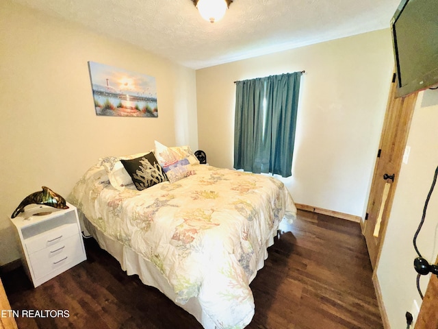 bedroom featuring dark wood-type flooring, a textured ceiling, and baseboards