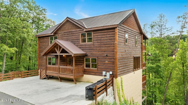 rustic home featuring metal roof, a patio area, and fence
