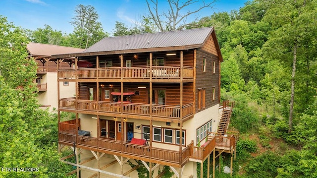 rear view of house featuring a balcony, stucco siding, and metal roof