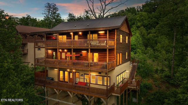 back of house with a balcony, metal roof, stucco siding, and an attached garage