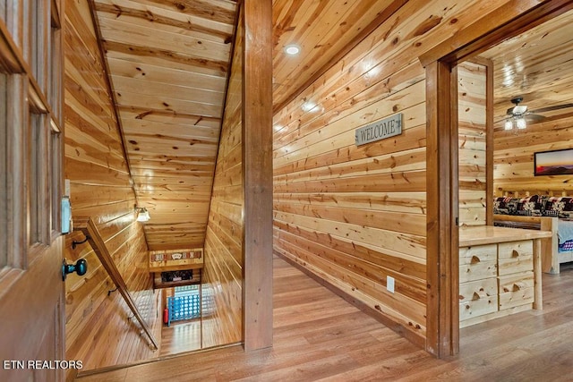 staircase with wooden walls, wood ceiling, wood finished floors, and ceiling fan