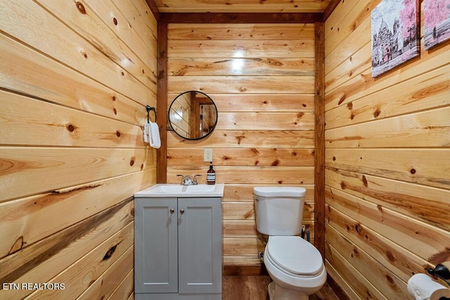 half bathroom with wooden walls, toilet, and vanity