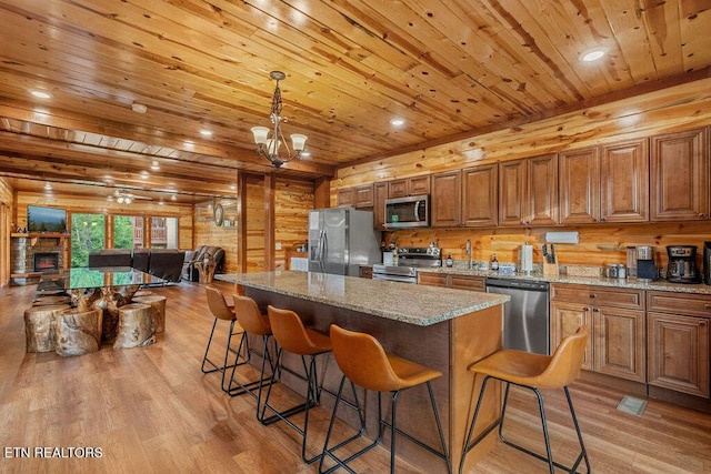kitchen with appliances with stainless steel finishes, wooden ceiling, light wood-type flooring, open floor plan, and a breakfast bar