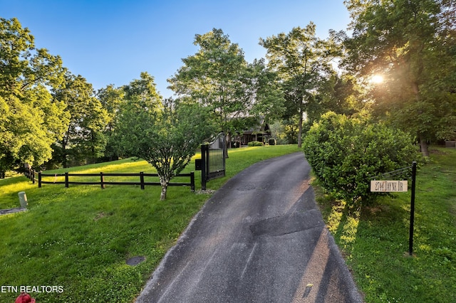 view of asphalt driveway with a gated entry and view of wooded area