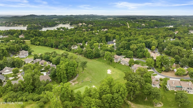 aerial view of residential area with a nearby body of water, a golf course, and a heavily wooded area