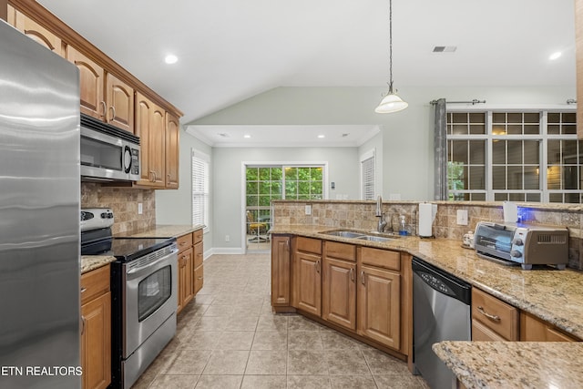 kitchen with appliances with stainless steel finishes, a sink, decorative backsplash, vaulted ceiling, and light stone countertops