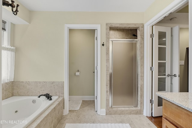 bathroom with a shower stall, a tub with jets, vanity, and tile patterned flooring