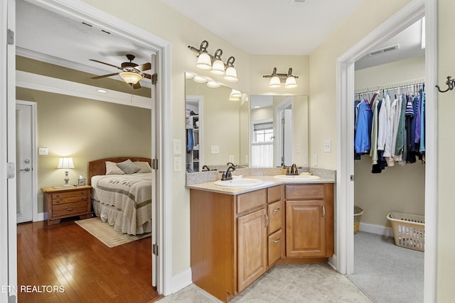 full bathroom with a ceiling fan, double vanity, connected bathroom, and baseboards