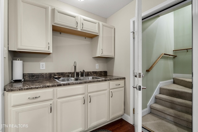 kitchen with a sink, dark countertops, and baseboards