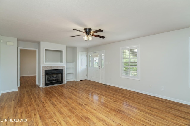 4419 Alder Tree Ln, Knoxville, TN 37938 - unfurnished living room featuring ceiling fan, a tiled fireplace, light wood-style flooring, and baseboards