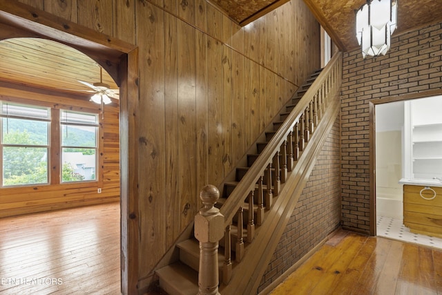 313 W Spring St, Oliver Springs, TN 37840 - stairs with hardwood / wood-style flooring, brick wall, wooden walls, and ceiling fan