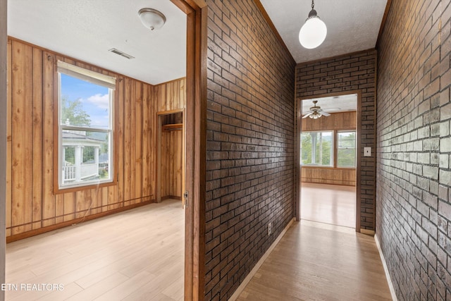 313 W Spring St, Oliver Springs, TN 37840 - hallway featuring light wood finished floors, brick wall, and a textured ceiling