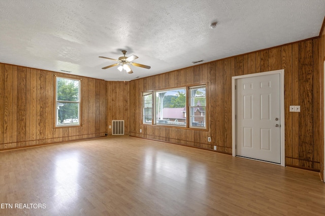 313 W Spring St, Oliver Springs, TN 37840 - unfurnished room with wood finished floors, a ceiling fan, wooden walls, a textured ceiling, and baseboards